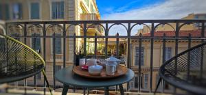 a table with a tray of food on a balcony at Le Petit Trianon et le Charme des Suites in Nice