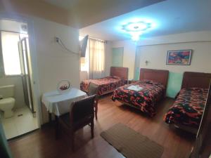 a room with two beds and a table and a room with a sink at Hotel Savoy in La Paz