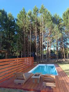 a swimming pool with two chairs and a wooden deck at Cabañas del Sol in Punta Del Diablo