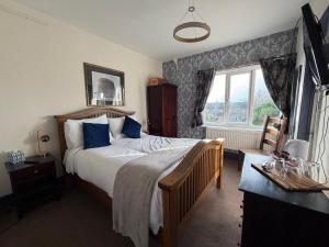 ein Schlafzimmer mit einem Bett mit blauen Kissen und einem Fenster in der Unterkunft Captain Howey Hotel in New Romney