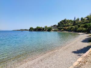 a beach with a rocky shore with trees in the background at Sunshine Home - Peaceful Garden Escape & Parking in Selianitika +20 photos