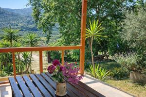 a wooden bench with a vase of flowers on a porch at Sunshine Home - Peaceful Garden Escape & Parking in Selianitika