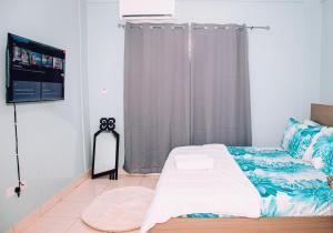a bedroom with a bed and a flat screen tv at Cosy Apartment with Pool in Kwabenyan
