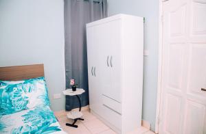 a bedroom with a white cabinet next to a bed at Cosy Apartment with Pool in Kwabenyan