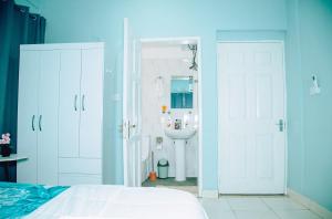 a bedroom with a bed and a bathroom with a sink at Cosy Apartment with Pool in Kwabenyan