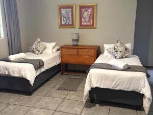a bedroom with two beds and a wooden dresser at Hekpoort Rorymi Guest farm in Hekpoort