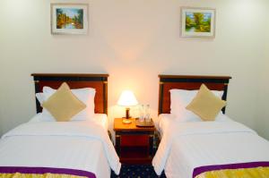 a bedroom with two beds and a table with a lamp at Jubail Inn in Al Jubail