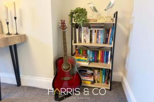 a guitar sitting next to a book shelf with books at Driftwood Bay in Fleetwood