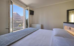 a bedroom with a large bed and a large window at Hotel Don Ferrante in Bellagio