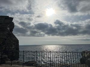 a view of the ocean with the sun behind a fence at Appartamento e Mansarda al mare in Rio Marina
