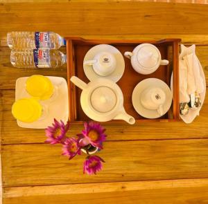 a wooden table with plates and utensils and a tray with flowers at Looma House Hiriketiya in Dickwella
