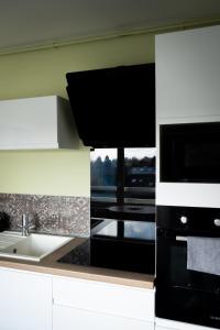 a kitchen with a sink and a microwave at Have a Cosy, Élégance in Grand-Fort-Philippe