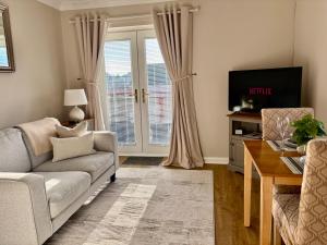 a living room with a couch and a tv at Kincraig Apartment in Ayr