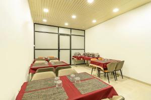 a dining room with tables and chairs with red tablecloths at Treebo Sairadha in Pune