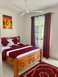 a bedroom with a large wooden bed with red curtains at Kendwa Crystal Coast Hotel in Kendwa