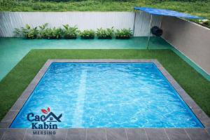 a swimming pool in a yard with an umbrella at Caca Kabin in Mersing