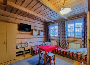 a room with two beds and a red table at CHAŁUPA Pokoje Gościnne in Poronin
