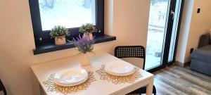 a white table with two plates and flowers on it at Quiet Apartment in Oświęcim