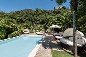 a swimming pool with chairs and an umbrella at Residence Fischerhof in Tirolo