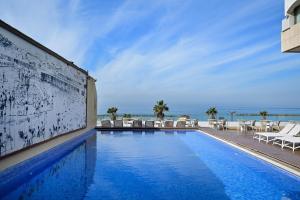 a swimming pool with chairs and the ocean in the background at (Floor Shelter)Luxury Sea View w/Pool Inside Hotel in Tel Aviv
