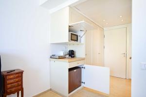 a small kitchen with white cabinets and a microwave at (Floor Shelter)Luxury Sea View w/Pool Inside Hotel in Tel Aviv