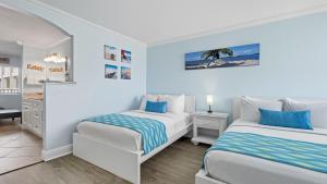 two beds in a white room with blue accents at Clearwater Beach Pelican 2 in Clearwater Beach +14 photos