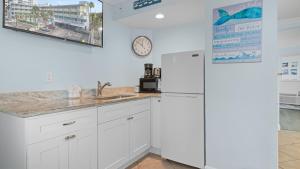 a kitchen with white cabinets and a refrigerator at Clearwater Beach Pelican 2 in Clearwater Beach
