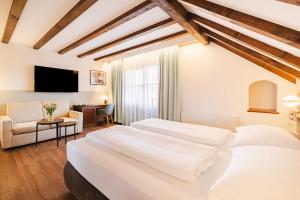 a bedroom with two beds and a chair and a television at Hotel Friesacher`s Aniferhof in Anif +24 photos
