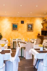 a restaurant with white tables and white chairs at Hotel Ariston in Piombino