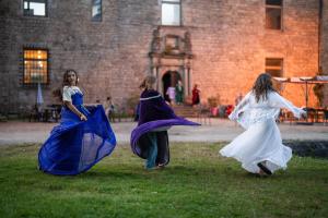 three girls in dresses running in front of a building at VVF Château sur la Vienne Lac de Vassivière in Nedde