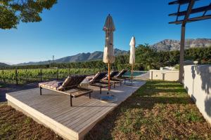 a row of lounge chairs and umbrellas on a wooden deck at The Manor House at Colmant in Franschhoek