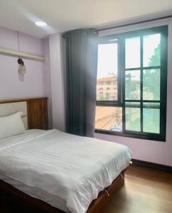 a bedroom with a bed and a large window at Zhejiang Pakxe Hotel in Pakse