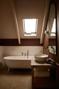 a bathroom with a tub and a sink and a window at The Manor House at Colmant in Franschhoek +6 photos