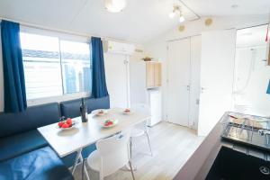 a kitchen and dining room with a white table and chairs at Camping Bella Austria - Maeva Vacansoleil in Sankt Peter am Kammersberg