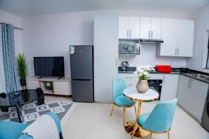 a kitchen with a table and blue chairs in a room at Lerako Apartment in Gaborone