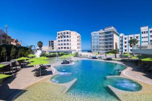 a large swimming pool with green umbrellas and buildings at BOUMERDES PLAZA Hôtel & Spa in Boumerdes
