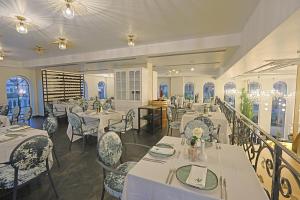 a restaurant with white tables and chairs and windows at Martiness Hotel Durres in Durrës
