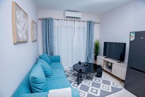 a living room with a blue couch and a tv at Lerako Apartment in Gaborone
