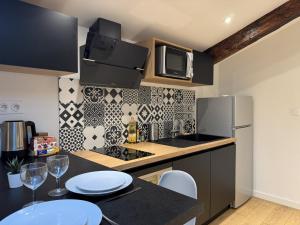 a kitchen with a table and a microwave and a refrigerator at Cocon Mansardé - Velux et Clim - Hyper Centre in Toulouse