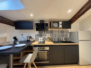 a kitchen with a table and a microwave and a refrigerator at Cocon Mansardé - Velux et Clim - Hyper Centre in Toulouse