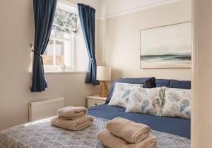 a bedroom with a blue bed with towels on it at Doug's Cottage in Elie