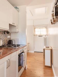 a kitchen with white cabinets and a wooden floor at Doug's Cottage in Elie
