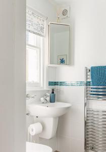 a white bathroom with a sink and a mirror at Doug's Cottage in Elie +26 photos