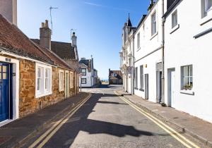 an empty street in a town with white buildings at Doug's Cottage in Elie
