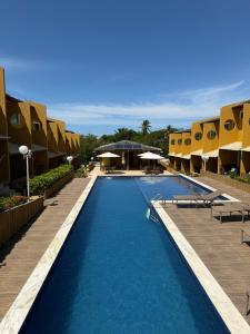 a pool at a resort with tables and umbrellas at Casa summer flats 23 Imbassai in Imbassai