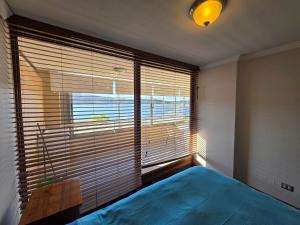a bedroom with a blue bed and a large window at Departamento Lago Vichuquen in Vichuquén Lake +85 photos