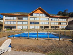 a building with a swimming pool in front of it at Departamento Lago Vichuquen in Vichuquén Lake