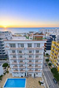 a building with a swimming pool in front of the ocean at Martiness Hotel Durres in Durrës
