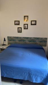 a blue bed in a bedroom with pictures on the wall at Appartamentino Bianco in Rio Marina