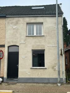 a house with a black door and two windows at Steves place Temse in Sint-Niklaas